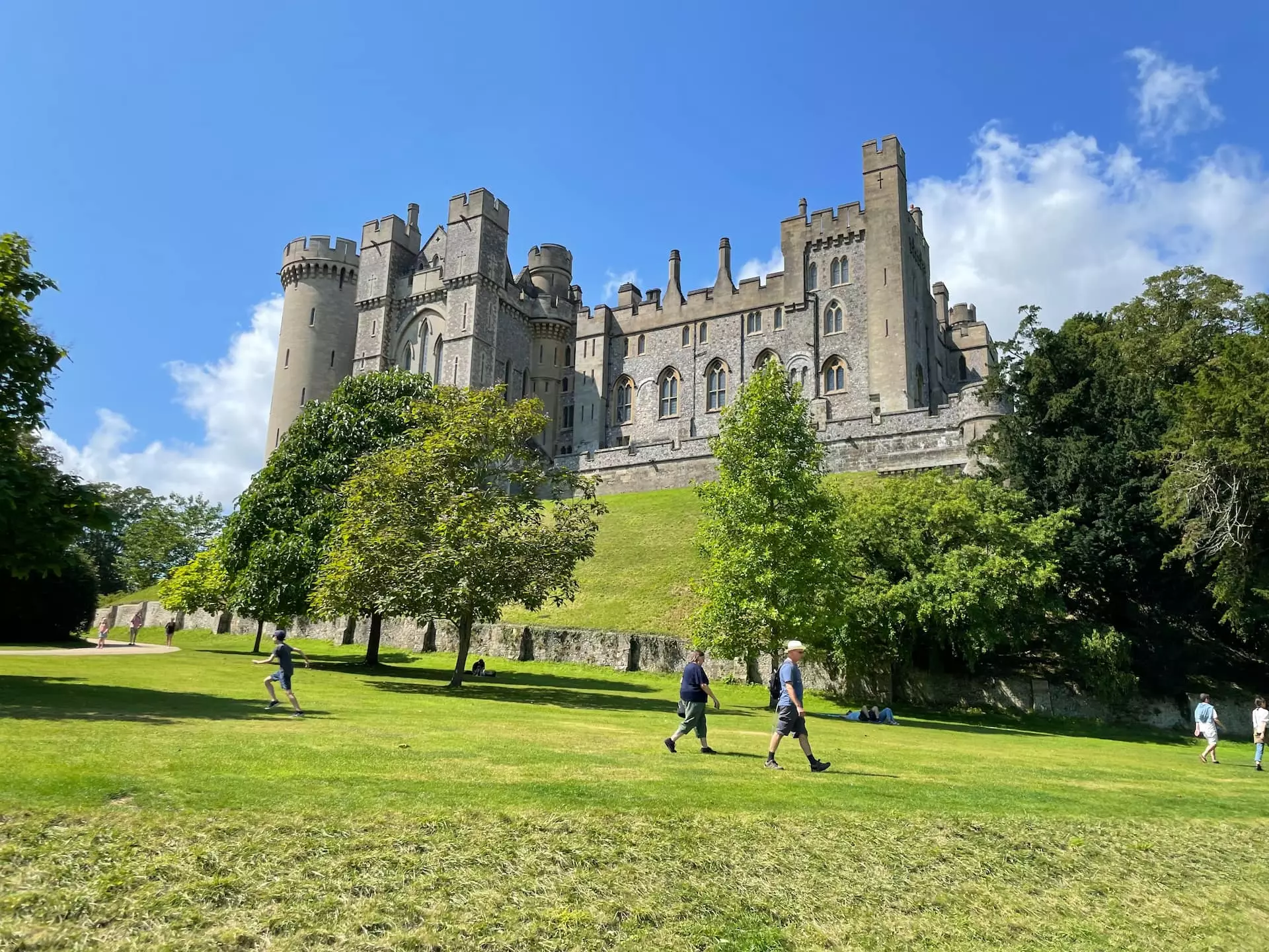 people walking on a grassy hill with a castle in the background