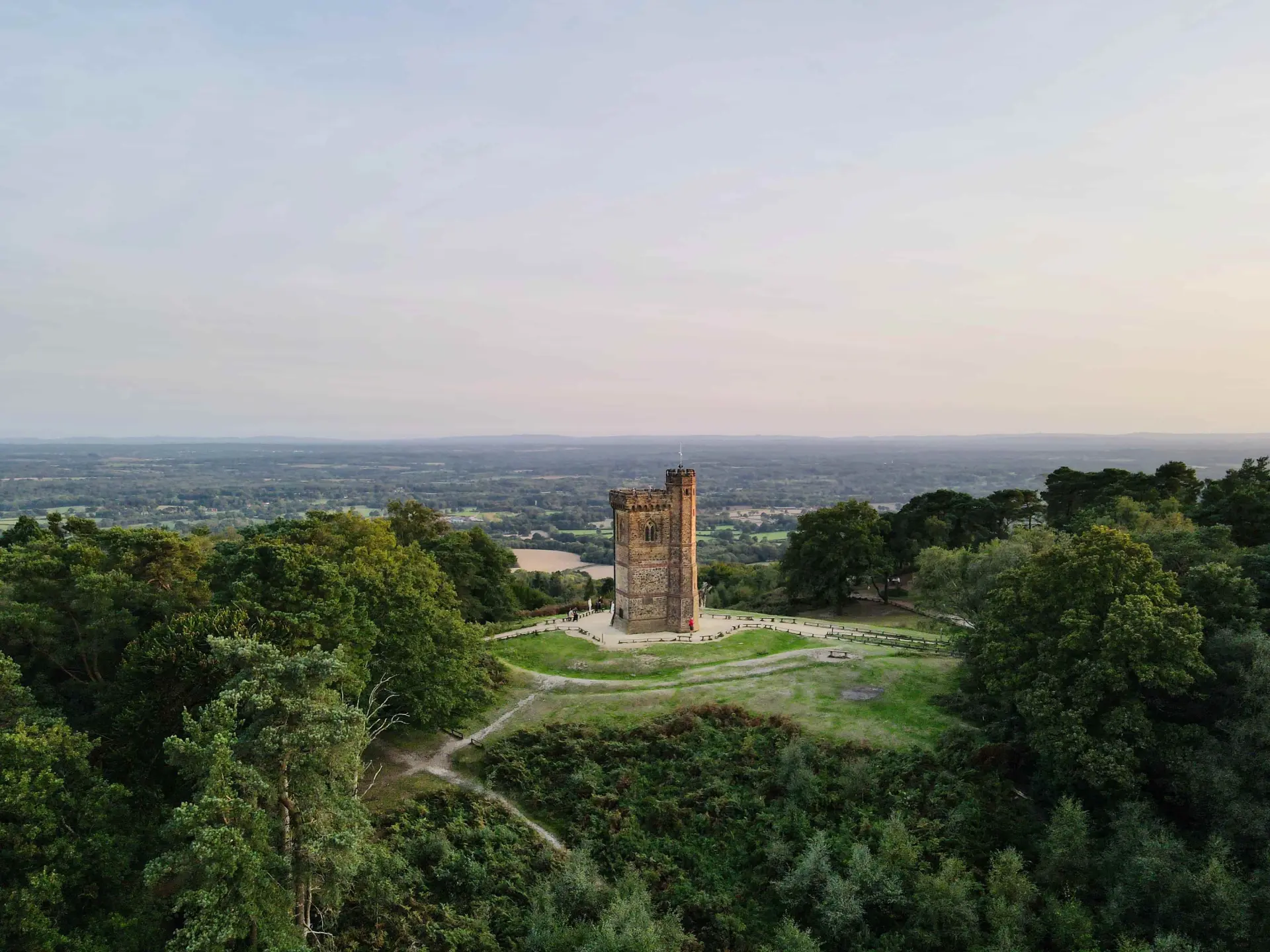 a tower on a hill with trees and a valley in the background