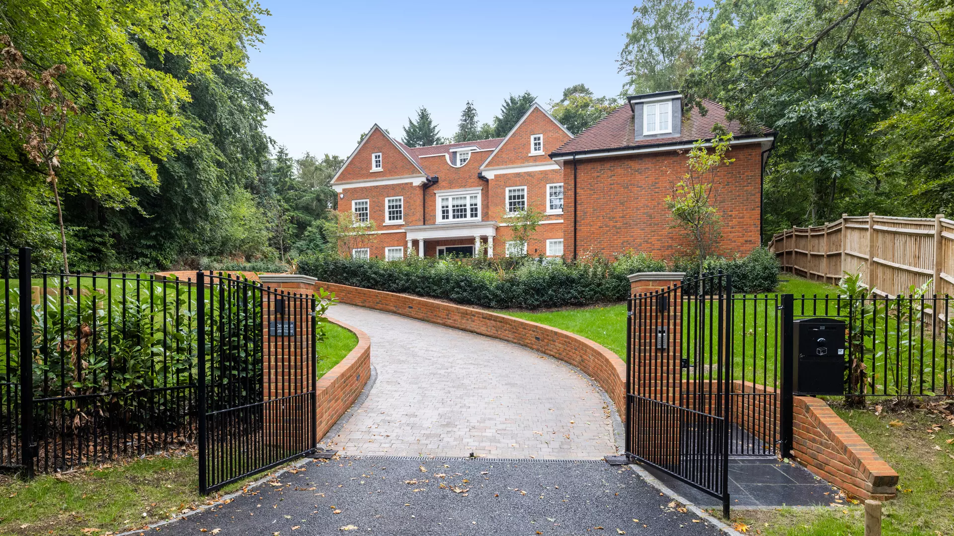 a gated driveway leading to a large brick house