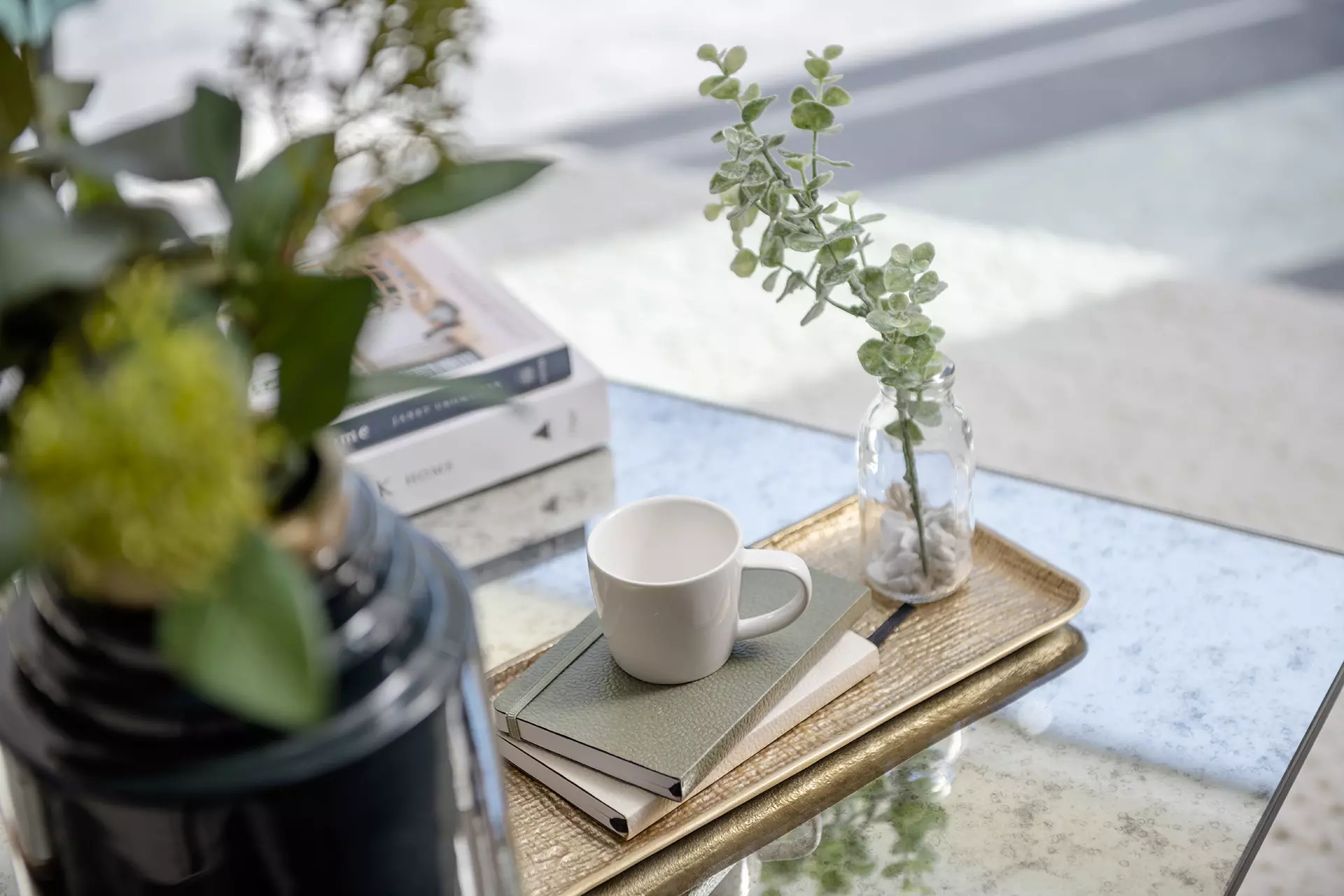 a coffee cup on a book and a vase of plants on a table