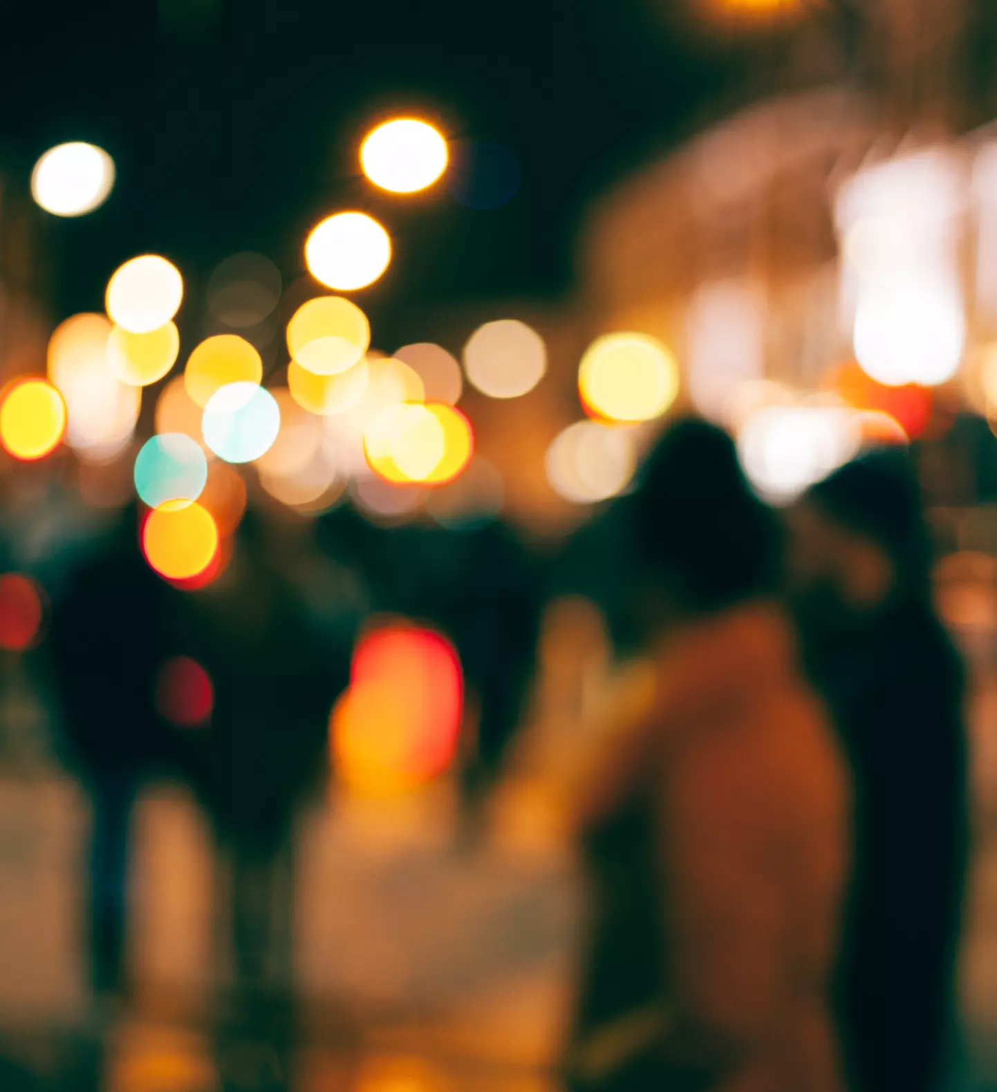 a group of people walking on a street at night