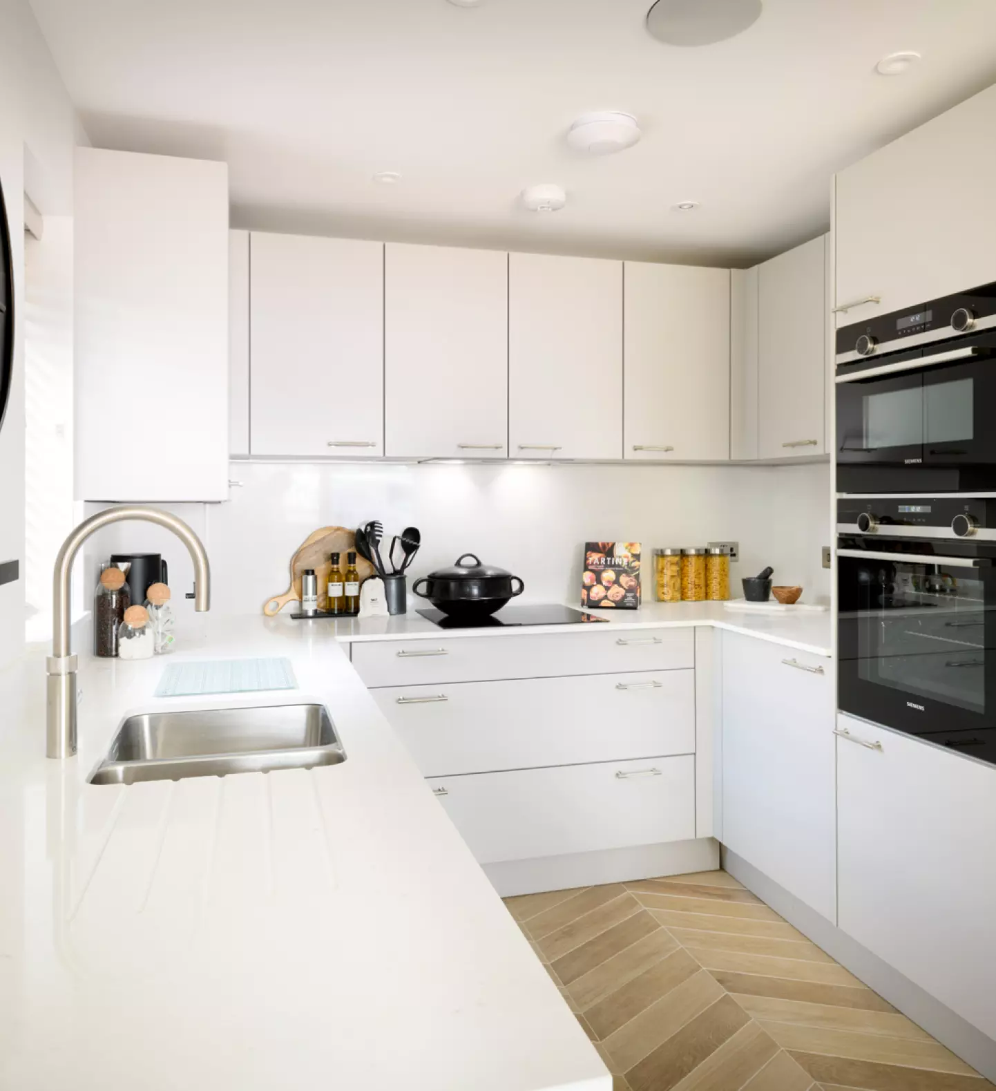 a kitchen with white cabinets and a black and white clock