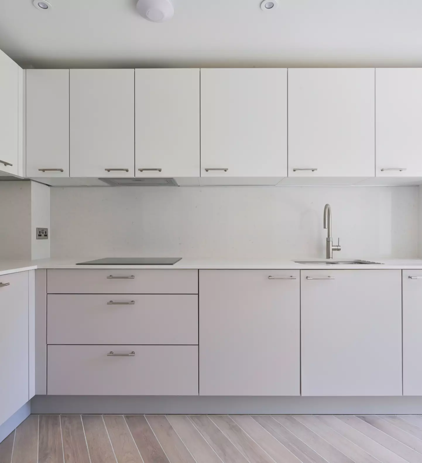 a white kitchen with white cabinets and a wood floor