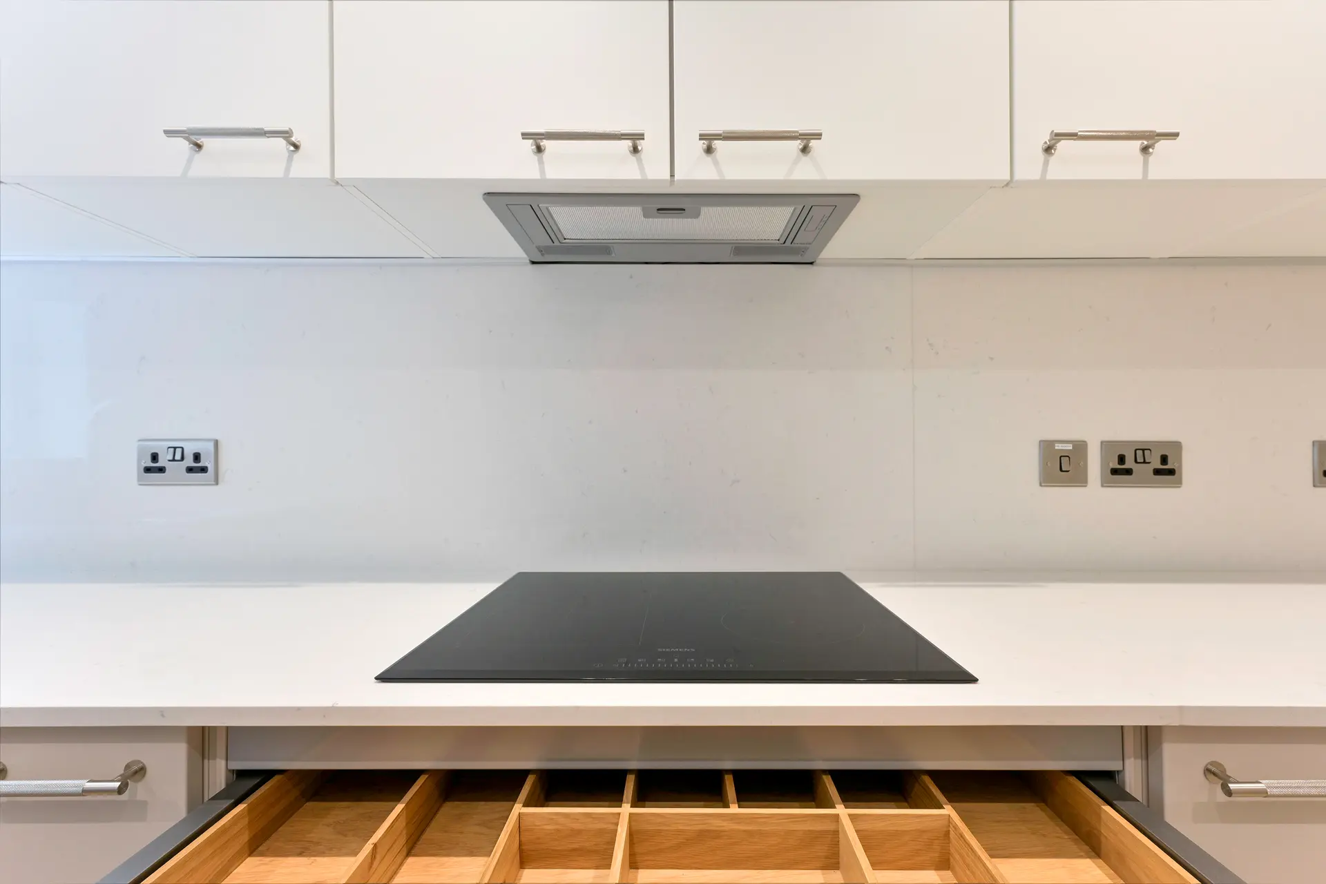 a white kitchen with a black stove and drawers