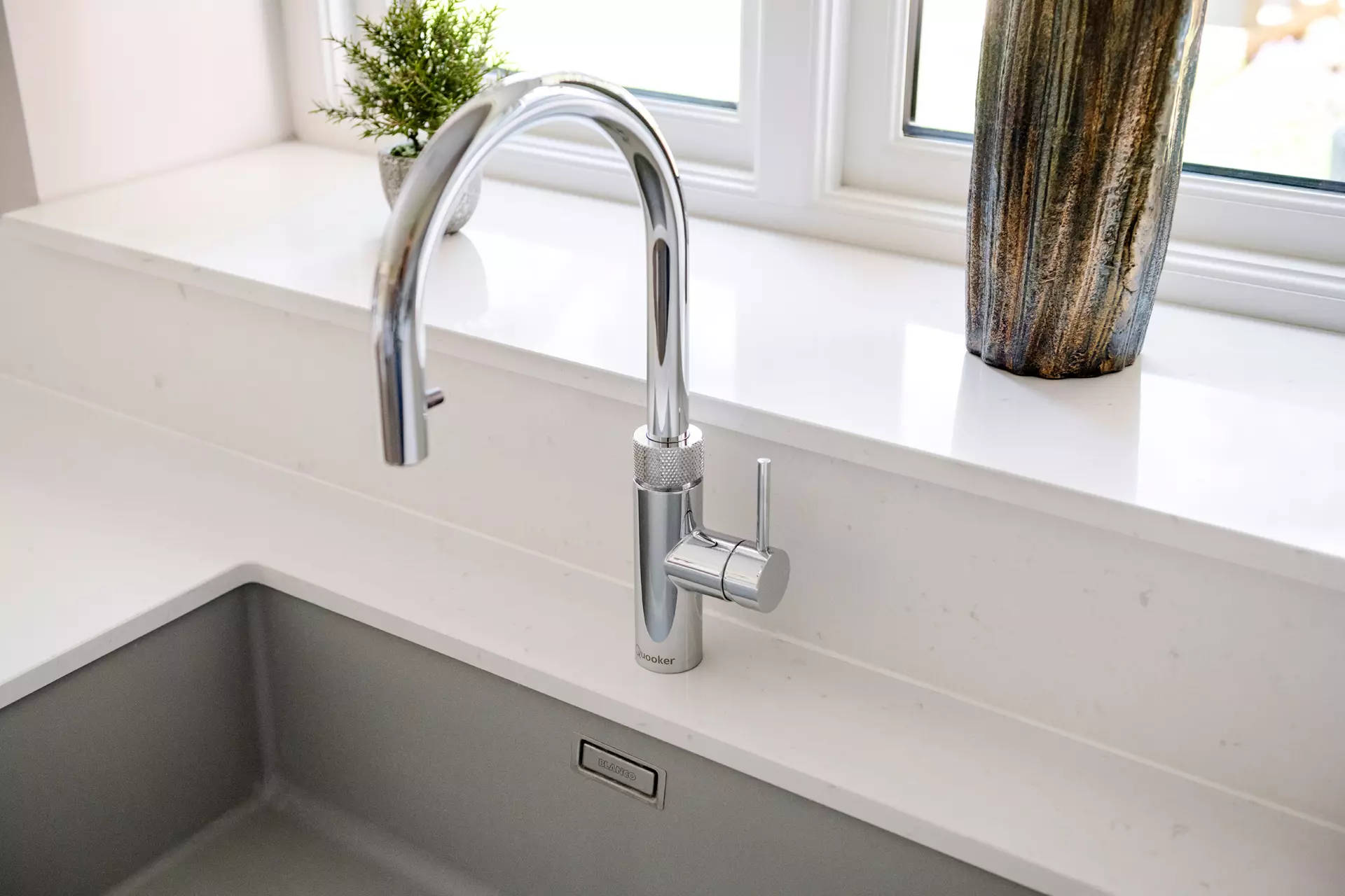 a sink with a faucet and a vase on the counter