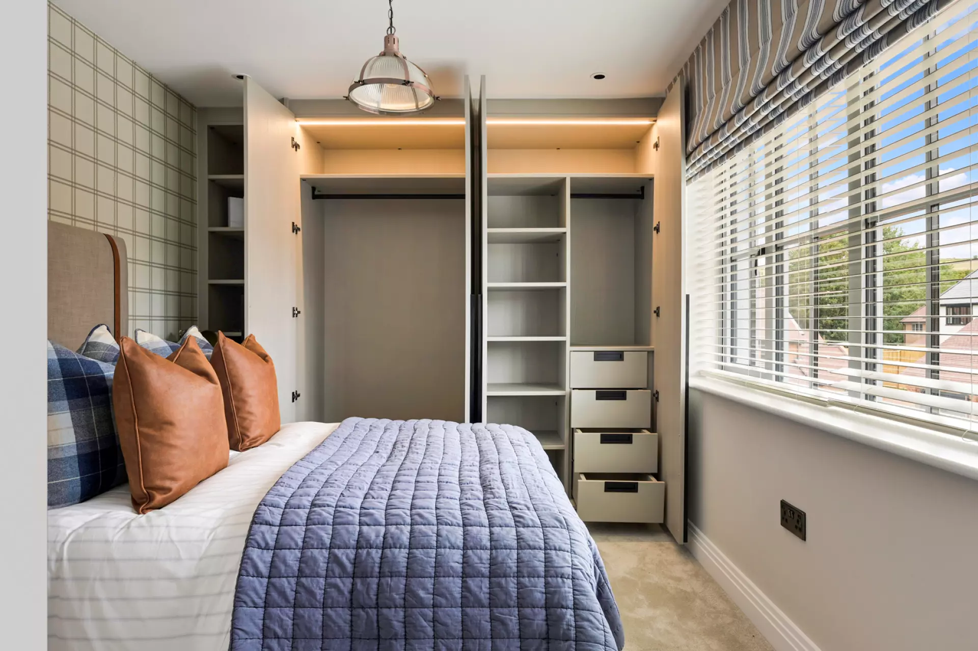 a bed with a blue blanket and brown pillows in a room with a closet