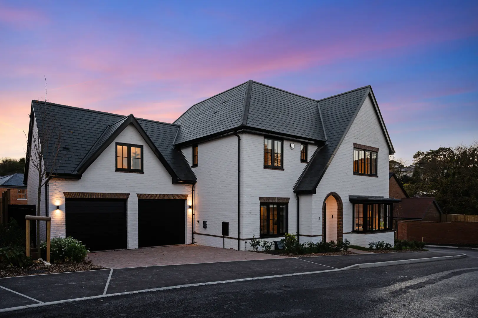 a house with a driveway and a purple and blue sky